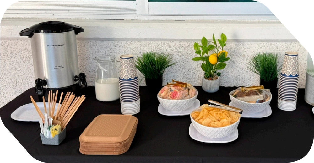 Estación de coffee break con cafetera industrial, tazas, galletas y bocadillos para reuniones de negocios y eventos corporativos en Salón Palmasola Cancún.